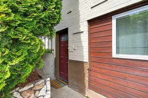 A house with a red door, a window with blinds, and a stone wall. - Deluxe West Seattle Apartment | Sleeps 6 | FIFA (Seattle)