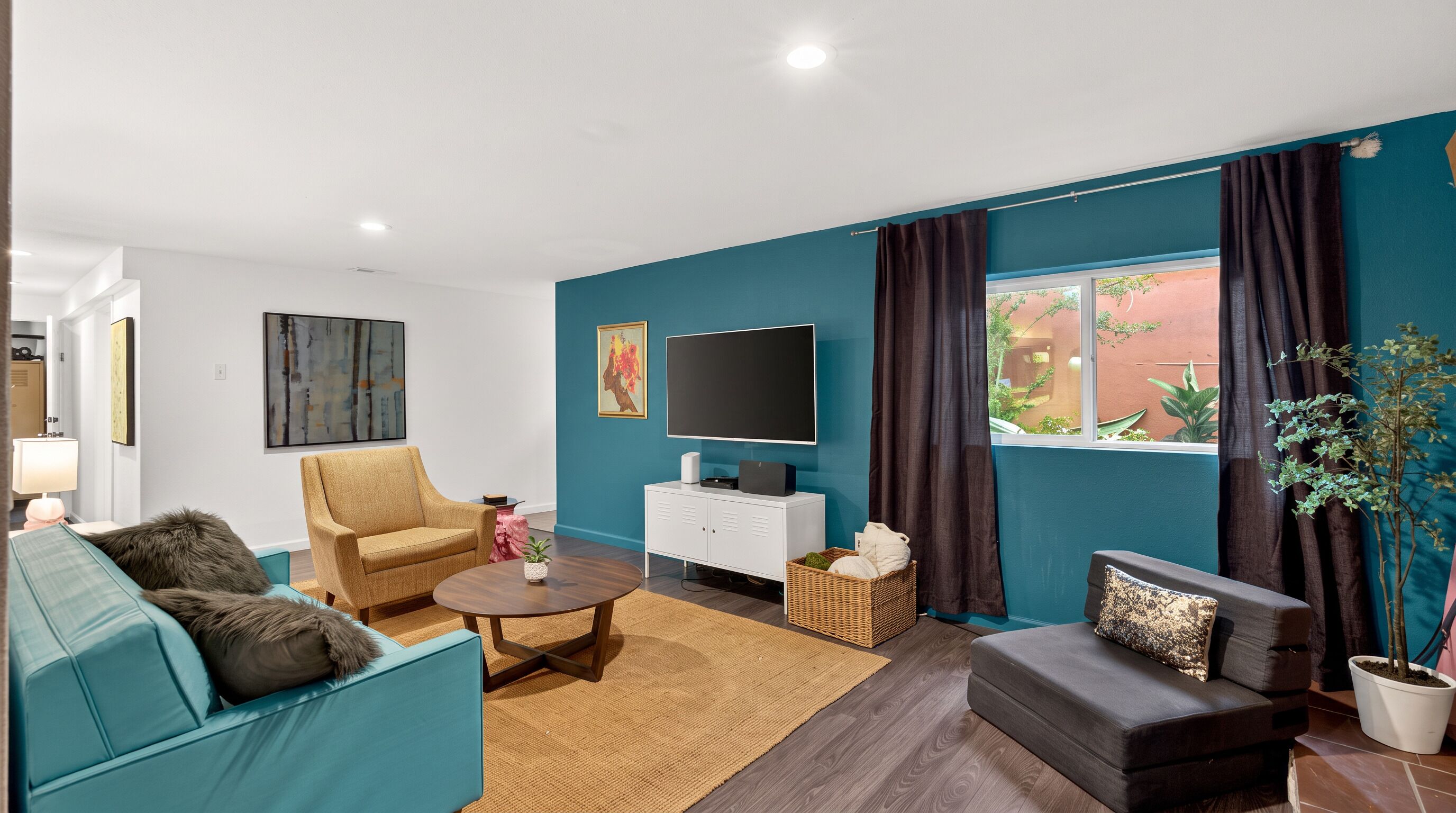 A modern living room with a sofa, armchair, coffee table, and a flat-screen TV on a white cabinet.