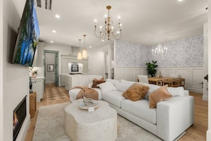 A modern living room with a sectional sofa, a fireplace, a dining area, and a kitchen in the background. - Luxury Alki Beach Villa | Sleeps 10 | 360° Rooftop (Seattle)
