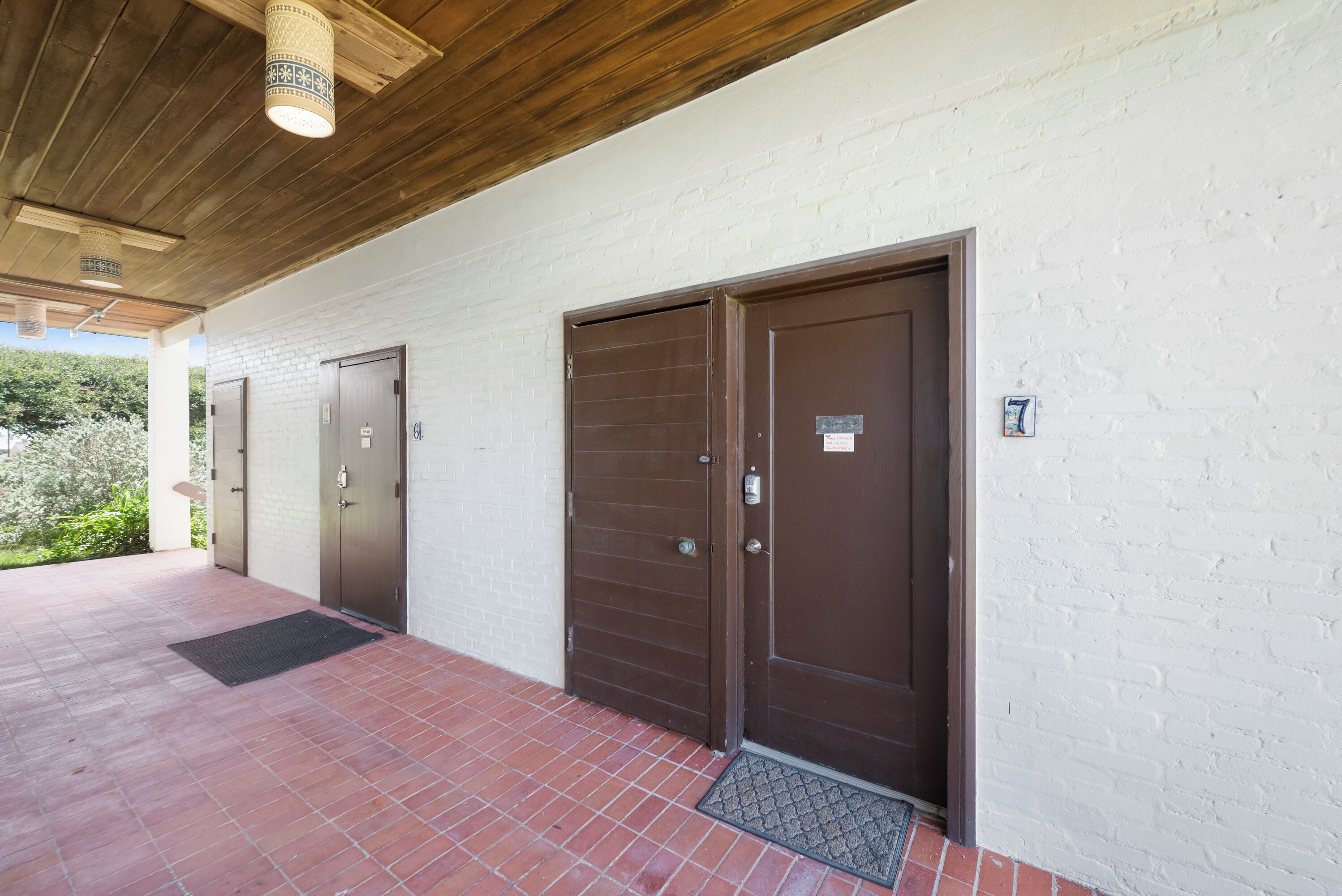 A building with two doors, a covered area with a tiled floor, and a white brick wall.