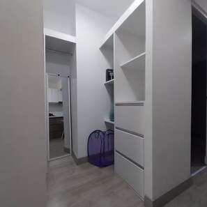 A walk-in closet with open shelves and a hanging bag. - Apartment with a beautiful view, downtown and a swimming pool (Lima)