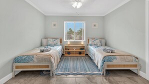 A bedroom with two beds, a window with blinds, a ceiling fan, and a bedside table with a lamp. - Heated Pool & Hot Tub, Walk to Beach, Fully Equipped. Free Bikes. Grill. (Naples)