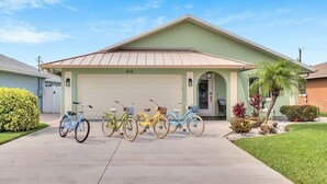 A house with a garage, a driveway, and a row of bicycles parked in front. - Heated Pool & Hot Tub, Walk to Beach, Fully Equipped. Free Bikes. Grill. (Naples)