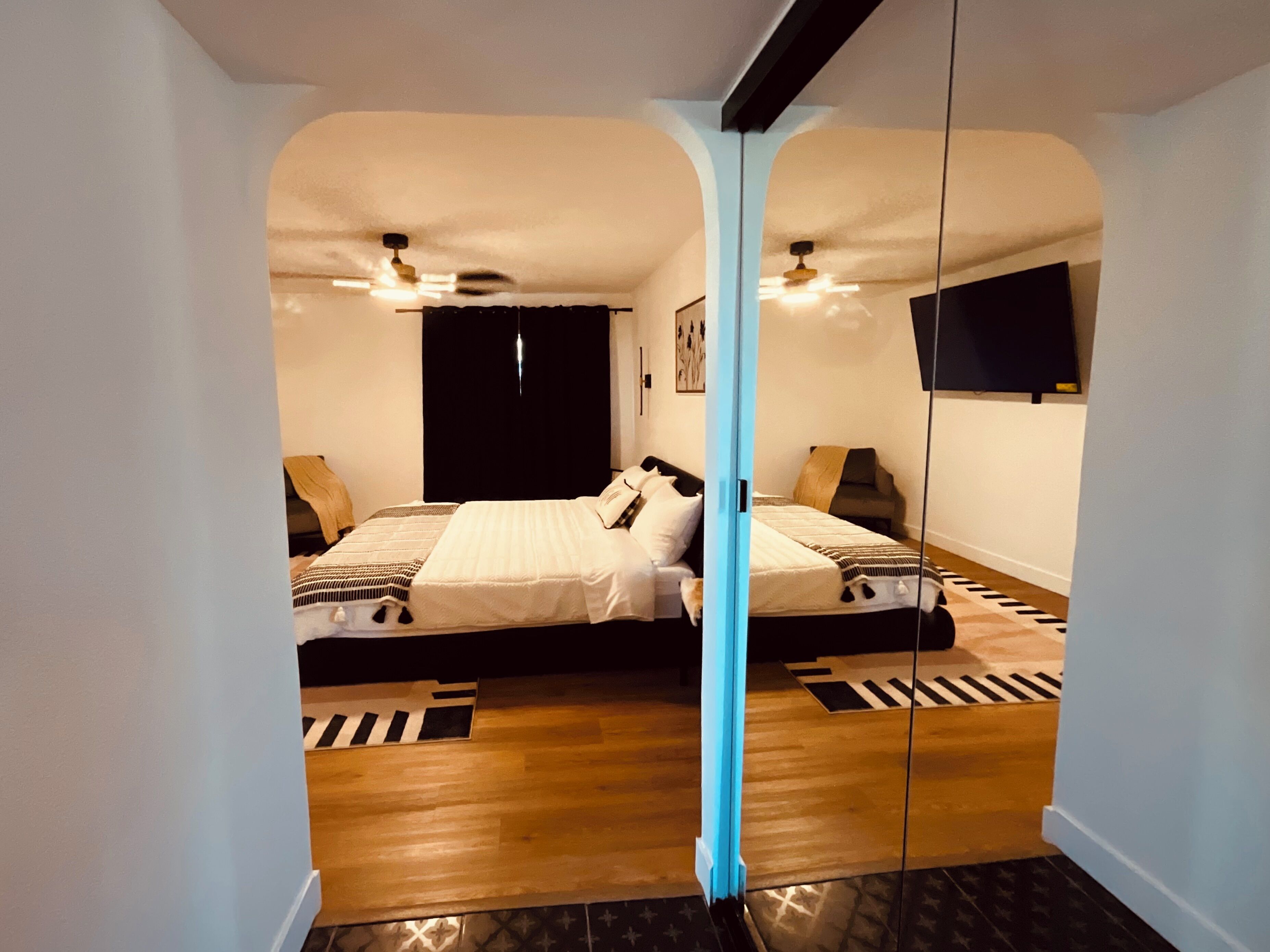 Een slaapkamer met twee bedden, een plafondventilator, een zwarte garderobe en een aan de muur bevestigde televisie.