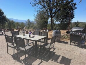 Un espacio al aire libre con zona de comedor, mesa y sillas, una parrilla y vistas a las montañas.