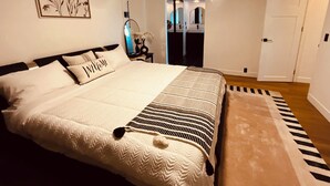 A bedroom with a large bed, a bedside table, a mirror, a door, and a wall-mounted picture. - Cozy 3-bedroom cabin in charming North Fork with AC (North Fork)