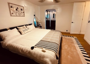 A bedroom with a large bed, a bedside table, a mirror, a door, and a wall-mounted picture. - Cozy 3-bedroom cabin in charming North Fork with AC (North Fork)