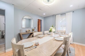 Ein Essbereich mit einem langen Tisch, Stühlen und einem Spiegel an der Wand.