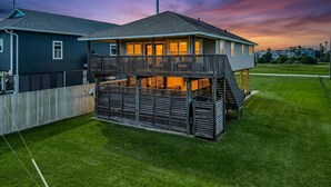 A two-story house with a balcony, a fenced yard, and a clear sky. - Sea Serendipity in Galveston (Galveston)