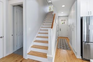 A staircase leading to a landing with a kitchen area, including a refrigerator and cabinets. - Sunset On Laurel – 3BR Golf Retreat, Golf Carts 🛺, Resort Amenities, Pets (Miramar Beach)