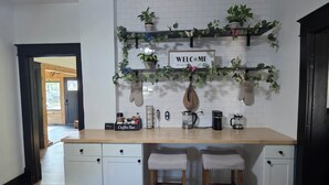 A kitchen with a white countertop, two bar stools, a coffee bar, and a welcome sign. - Quaint home that sleeps 9, 3 blocks from the Beach. Private back yard with bar. (Culver)