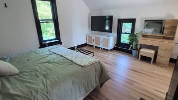 Une chambre à coucher avec un lit, un ventilateur de plafond, une télévision, une fenêtre et une plante.