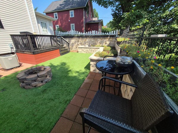 A backyard with a fire pit, a patio table, and chairs.