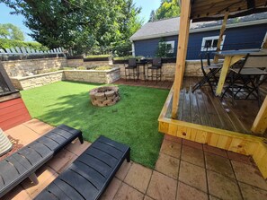 A backyard with a fire pit, outdoor seating, and a covered patio area.