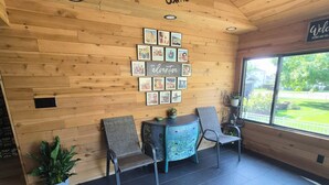 A reception area with wooden walls, a ceiling fan, a wall-mounted photo collage, and a window with a view of the outdoors. - Quaint home that sleeps 9, 3 blocks from the Beach. Private back yard with bar. (Culver)