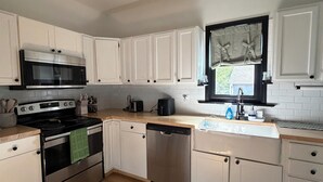 A modern kitchen with white cabinets, a stainless steel stove, and a dishwasher. - Quaint home that sleeps 9, 3 blocks from the Beach. Private back yard with bar. (Culver)