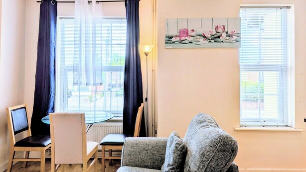 Ein Zimmer mit Esstisch, Stühlen, einer Couch, einer Lampe und einem Bild an der Wand.
