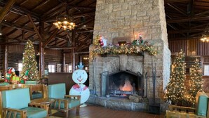 A rustic lodge interior with a stone fireplace, wooden furniture, and Christmas decorations. - Starved Rock Lodge & Conference Center (Oglesby)