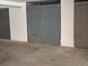 Eine geschlossene Metalttür mit Schlüsselloch, ein Betonboden und eine weiße Wand.