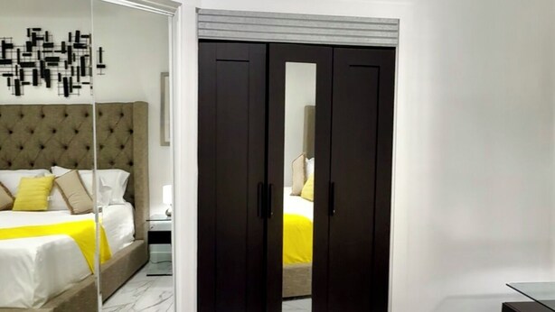 Une chambre d’hôtel moderne équipée d’un lit, d’une armoire et d’un miroir.
