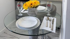 Une cuisine moderne avec des meubles blancs, un four à micro-ondes, un évier et une table en verre agrémentée d’un vase de fleurs jaunes.