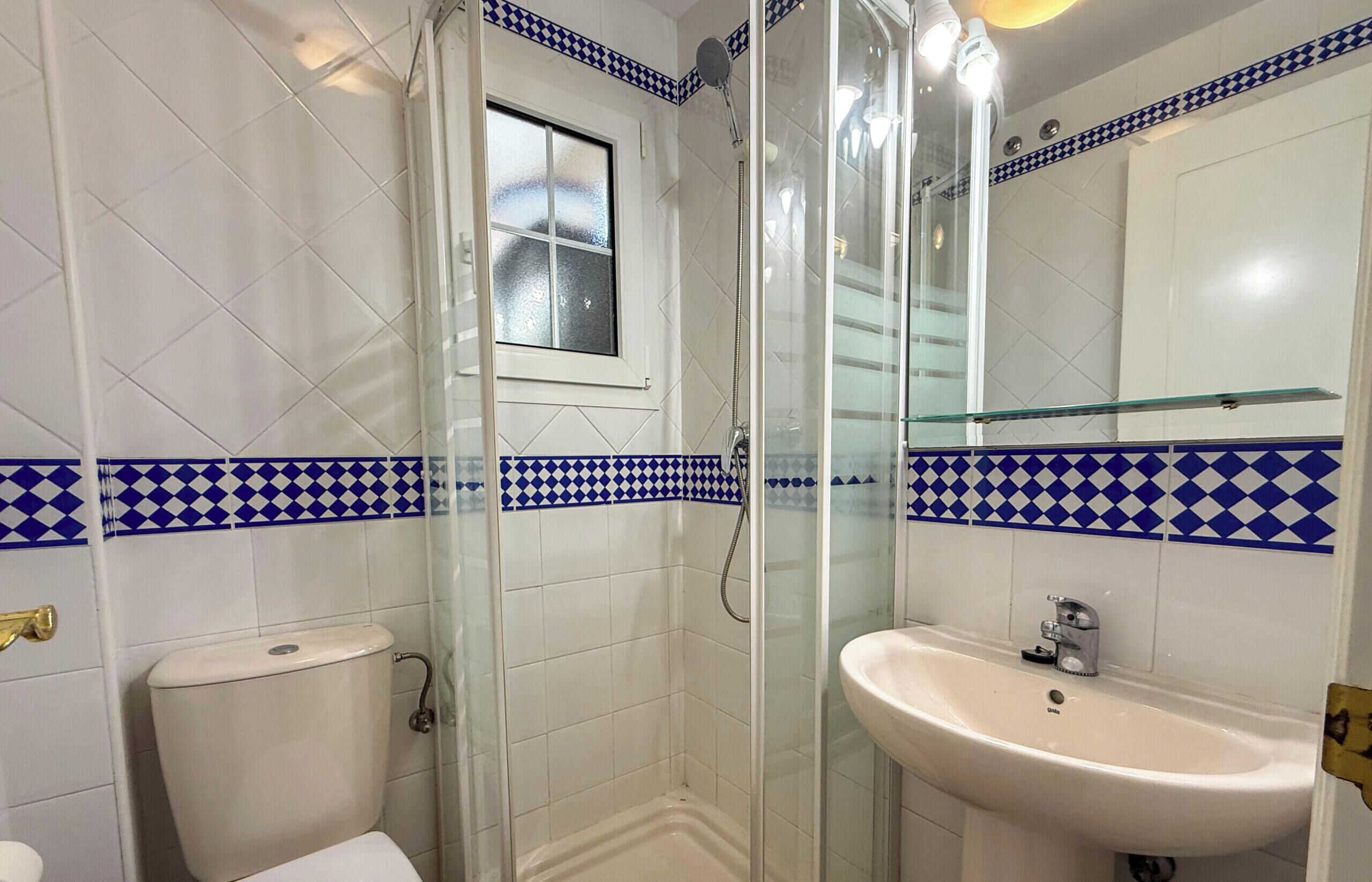 Ein Badezimmer mit einer Duschkabine, einer Toilette und einem Waschbecken mit Spiegel darüber.