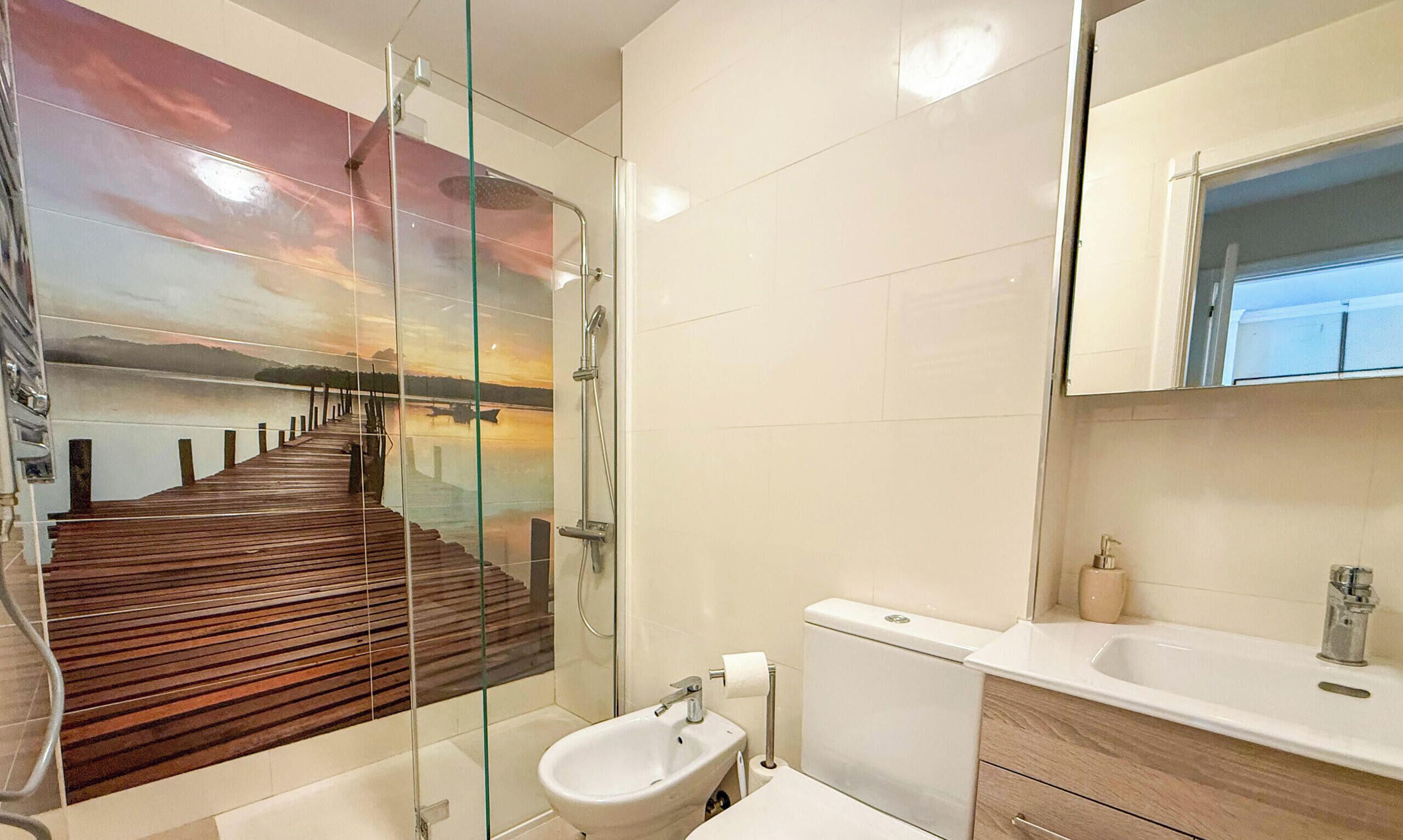 Een moderne badkamer met een glazen douchecabine, een bidet en een grote spiegel.