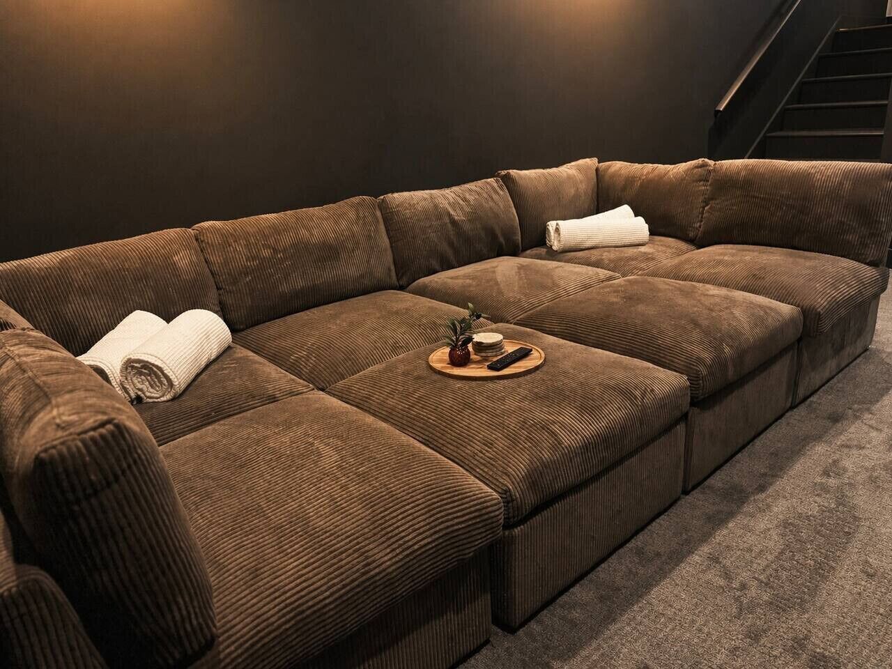 A sectional sofa with a remote control and a small plant on a tray.
