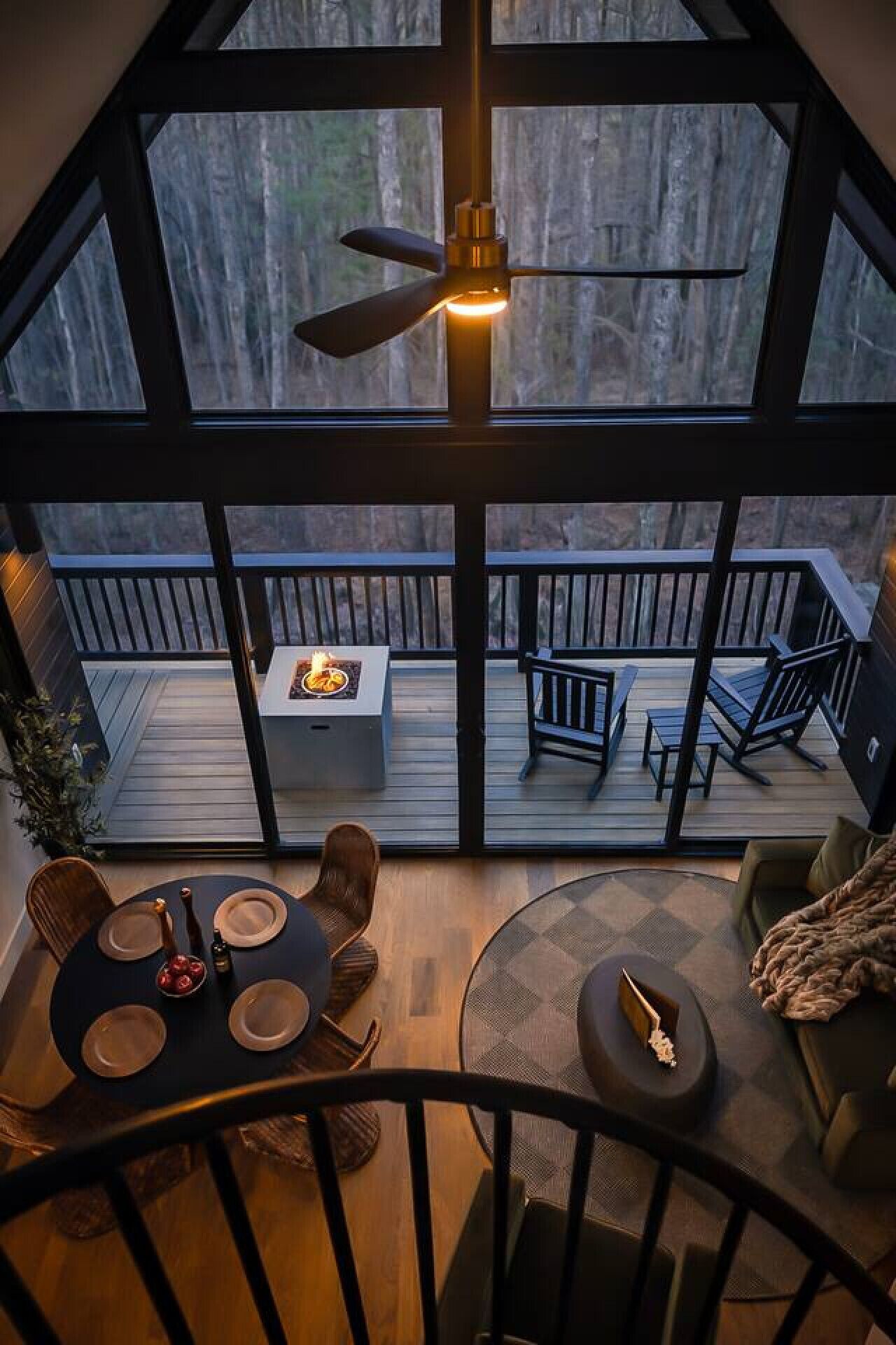 Una habitación con techos altos, un área de comedor, un ventilador de techo y vistas a una terraza exterior.