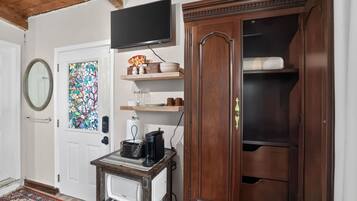 A room with a wooden cabinet, a television, a coffee maker, and a decorative glass door.