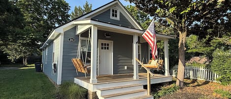Een gelijkvloers huis met een veranda, een schommel en een Amerikaanse vlag.
