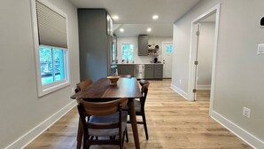 Une cuisine moderne avec un coin repas, un plancher en bois et une vue sur l’extérieur.