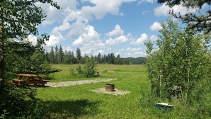 A picnic table in a grassy field with trees in the background.
