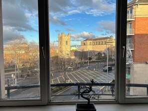 A view through a window of a city street with a historic building, a modern building, and a tree in the foreground. - Central 2BR Flat w/balcony Near Temple Bar (The Liberties)