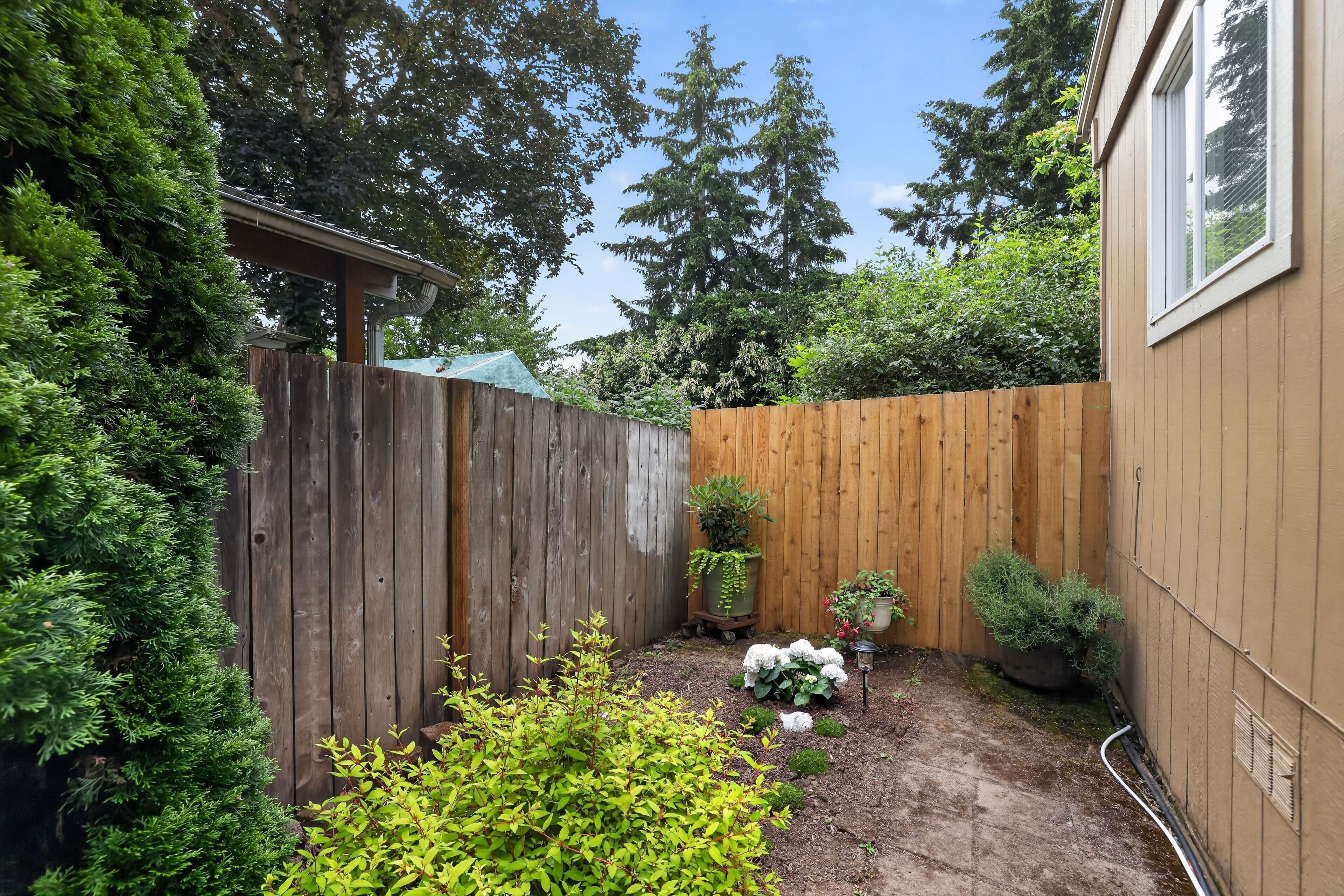 A wooden fence, potted plants, and a garden area with a wooden deck.
