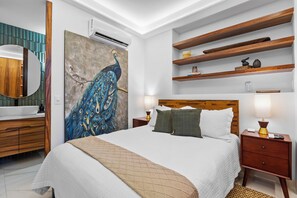 A bedroom with a large bed, bedside tables, a nightstand, a wall-mounted shelf, and a peacock painting. - Luxury 2B Romantic Zone Condo , Rooftop Pool, 2-Min Walk to Beach (Puerto Vallarta)