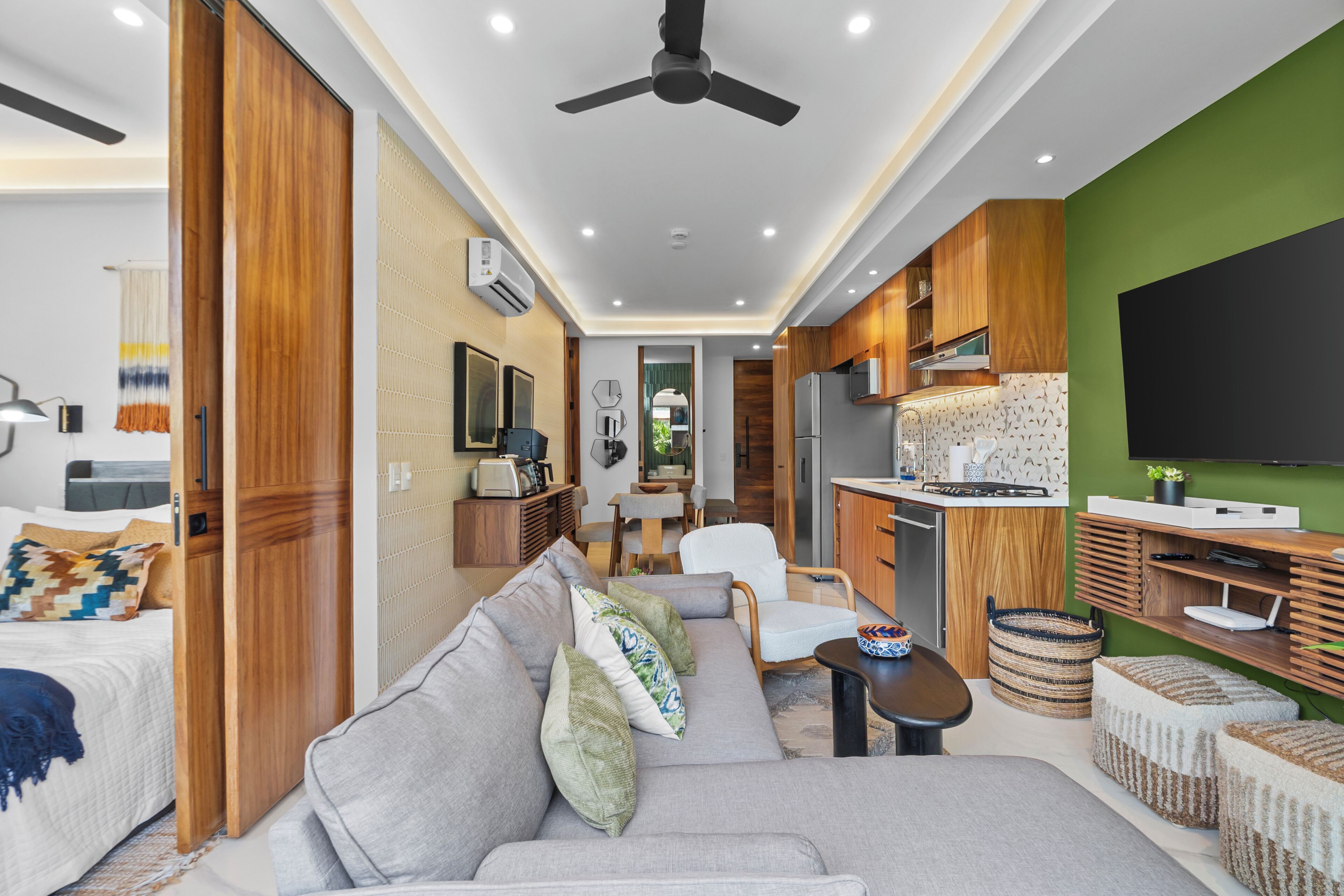 A compact living space with a kitchenette, a sofa, a dining area, and a television.