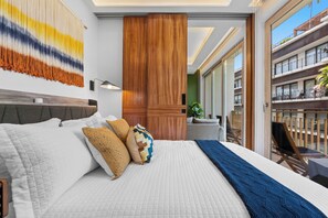 A hotel room with a large bed, a wooden headboard, a wall-mounted lamp, and a view of the outside balcony. - Luxury 2B Romantic Zone Condo , Rooftop Pool, 2-Min Walk to Beach (Puerto Vallarta)