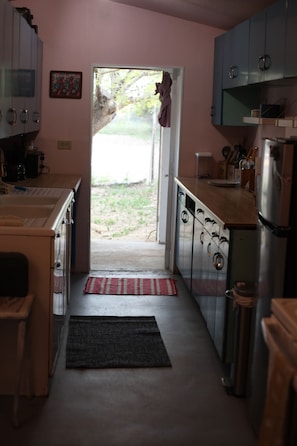 A kitchen with cabinets, a refrigerator, and a door leading outside.