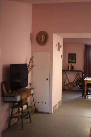 A room with a television, a wooden desk, a bicycle, and a door.