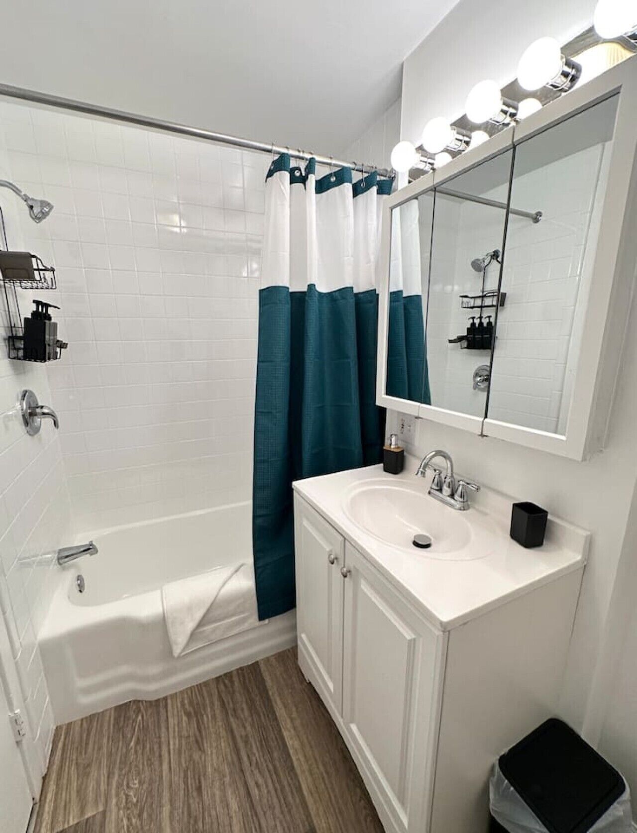 A bathroom with a bathtub, a sink, a mirror, and a shower curtain.