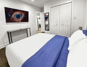 A hotel room with a large bed, a desk, a mirror, and a galaxy-themed wall art. - Galactic Getaway - 15 Min to Midway - Easy Access to Chicago (Berwyn)