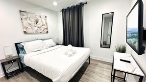 Une chambre à coucher moderne avec un lit, une table de chevet et un grand miroir.