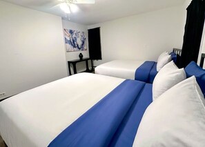 Ein Hotelzimmer mit zwei Betten, einem kleinen Tisch und einem Kunstwerk an der Wand.