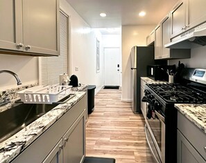 Eine moderne Küche mit einer Granit-Arbeitsplatte, Edelstahlgeräten und Holzboden.