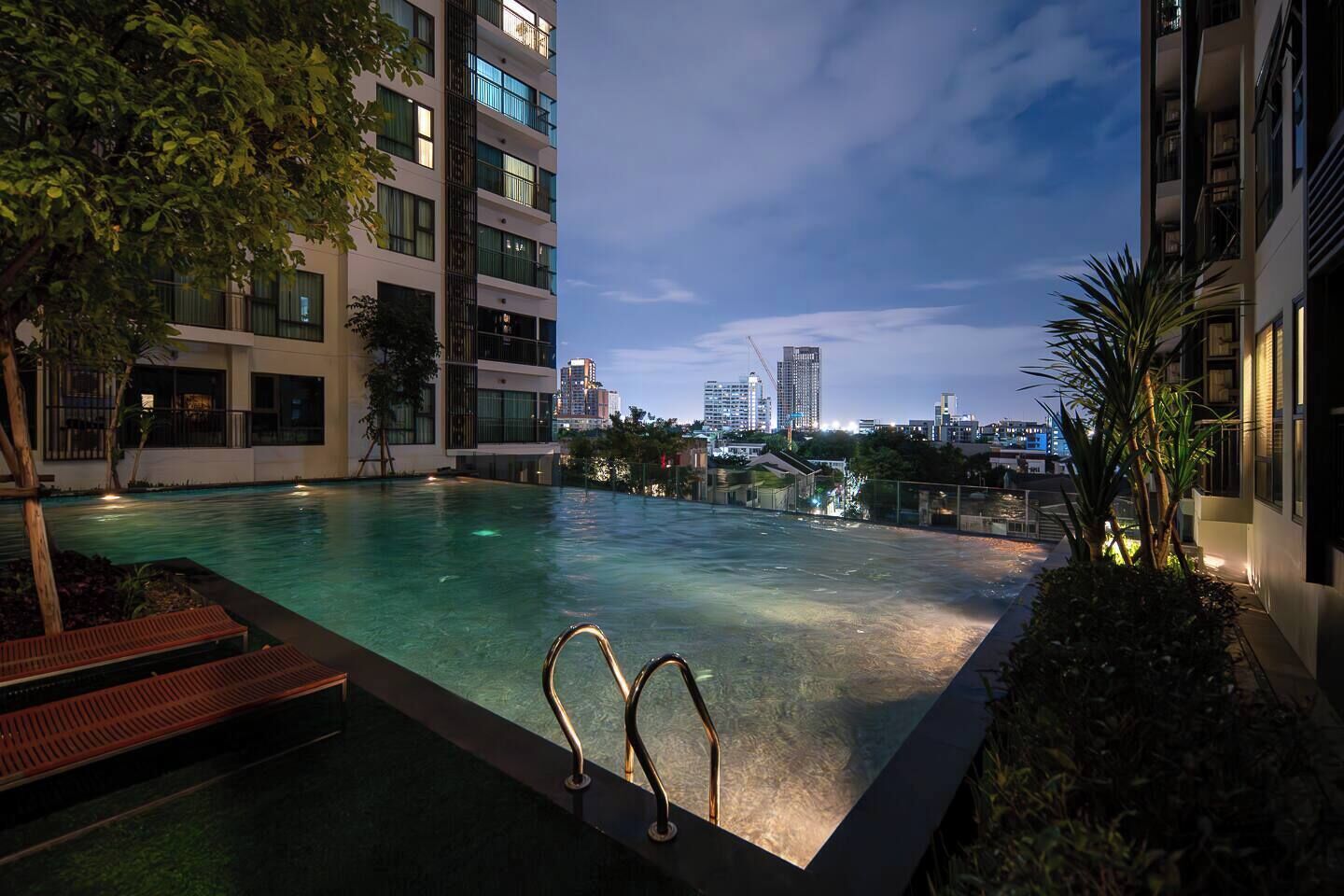 A rooftop pool with a city view, surrounded by modern buildings and trees.