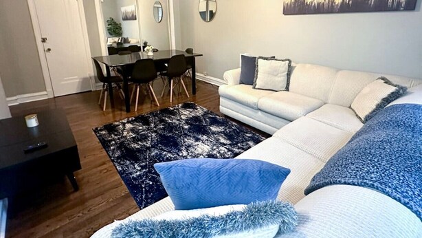 Una sala de estar con sofá, una mesa de centro, un tapete y un comedor con sillas y una mesa.