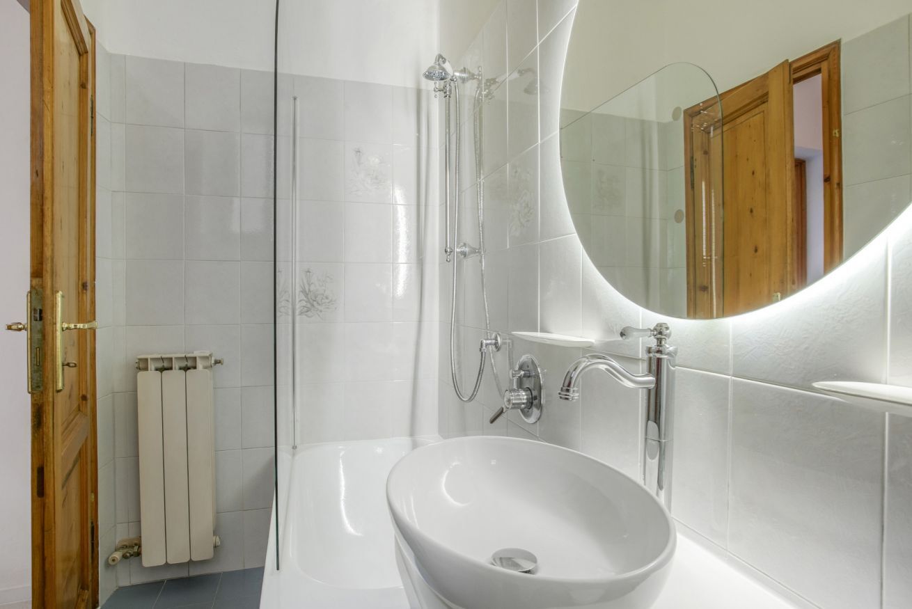 Une salle de bain moderne avec une douche à parois de verre, un lavabo blanc et un grand miroir.
