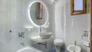 Een moderne badkamer met een bad, een wastafel, een toilet en een bidet.