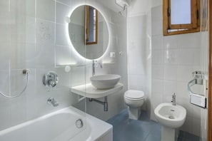 Ein modernes Badezimmer mit einer Badewanne, einem Waschbecken, einer Toilette und einem Bidet.